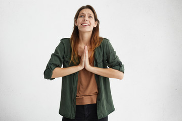 Wall Mural - Headshot of young student female in casual clothes begging for good luck at exam. Pretty woman with dark straight hair asking for help having hopes for good. Hopeful, emotional woman praying