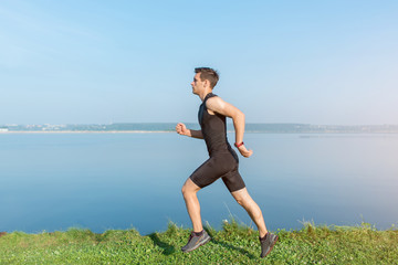 Athlete running man jogging on beach. Morning workout in summer