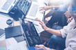 Young coworkers working on laptop computer at office.Woman holding tablet hand and pointing on touch screen with graphs and diagram. Horizontal, blurred background.Cropped.