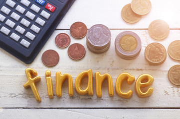 Finance word on wood table ,pile coin money with calculator, concept in grow and walk step by step for success in business