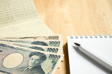 Canvas Print - Bank passbook with japanese yen and book with pen on wood table background