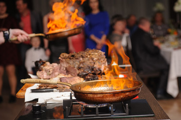 Cooking show, chef cooks, fries meat in a frying pan with fire