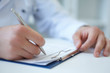Male medicine doctor hand holding silver pen writing something on clipboard closeup. Ward round, patient visit check, medical calculation and statistics concept. Physician ready to examine patient