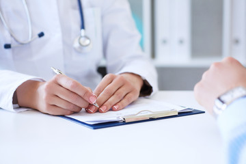 Female doctor filling medical form while consulting patient