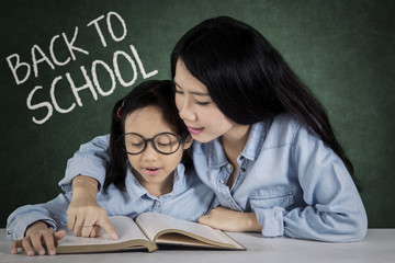 Little girl and teacher read a book