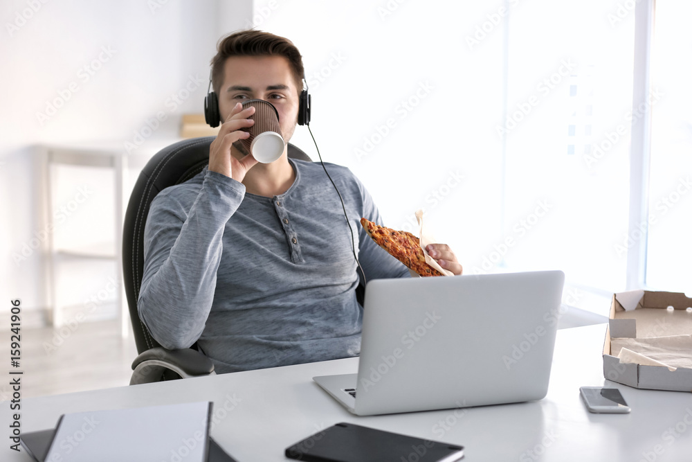 Young handsome man having a break and drinking coffee at work
