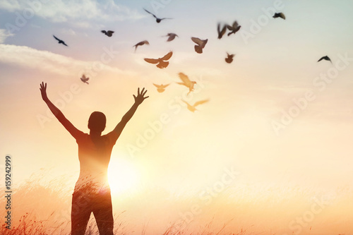 Photographie Woman praying and free bird enjoying nature on sunset background, hope concept