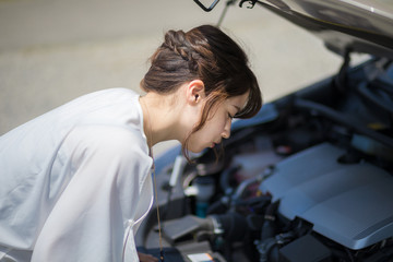 young woman checking under the hood.