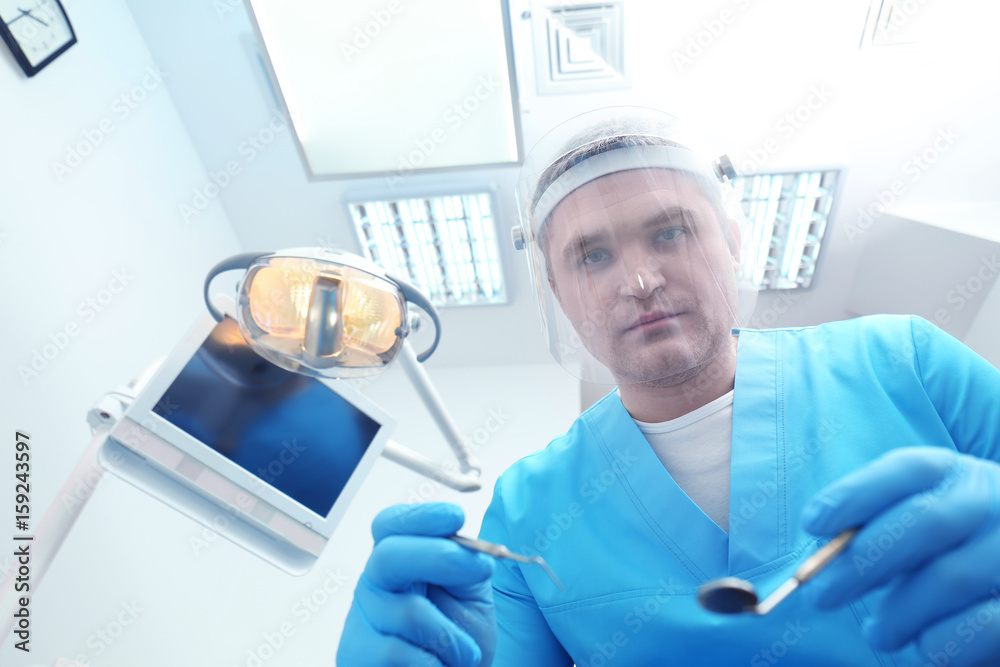 Dentist with mirror and periodontal explorer in clinic