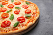 © Africa Studio - Delicious pizza with tomatoes, basil and melted cheese on grey background