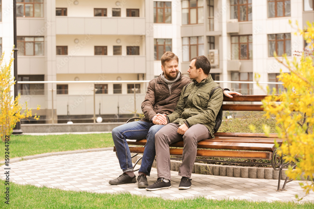 Romantic gay couple sitting on bench
