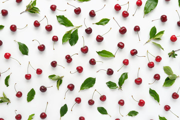 Wall Mural - Cherries and green leaves isolated on white background. Pattern of cherry with green leaves. Abstract food background. Top view.