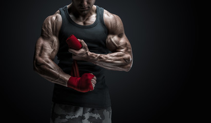 Strong man wrap hands on black background Man is wrapping hands with red boxing wraps isolated on black background Strong hands and fist, ready for training and active exercise