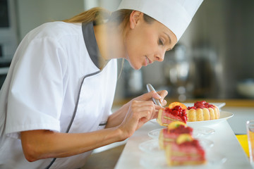 Portrait of pastry chef cutting slices of cake for serving