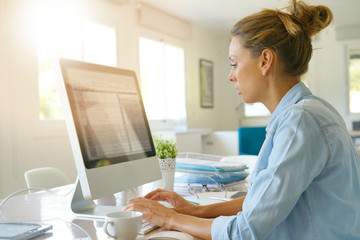 Wall Mural - Beautiful young woman in office working on desktop computer