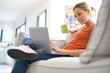 © goodluz - Woman websurfing on internet with laptop, sitting in couch