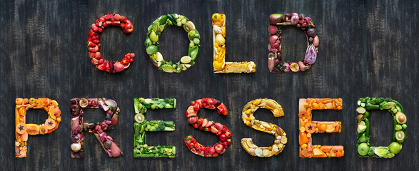 Wall Mural - Cold pressed juice vegetables words spelled out with healthy organic fruit on rustic background