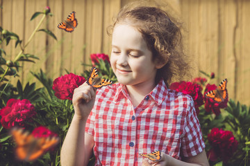 Wall Mural - Curly girl with a butterfly on his finger.