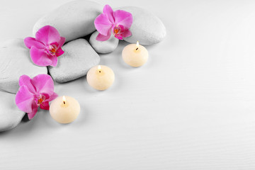 Sticker - Spa stones with orchid flowers and burning candles on white background