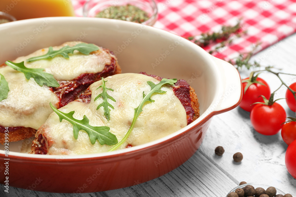 Chicken parmesan with spices in baking dish on table