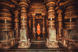 Lonely woman standing in center of ancient Hindu temple with stone columns, India. Traditional architecture of Asia.