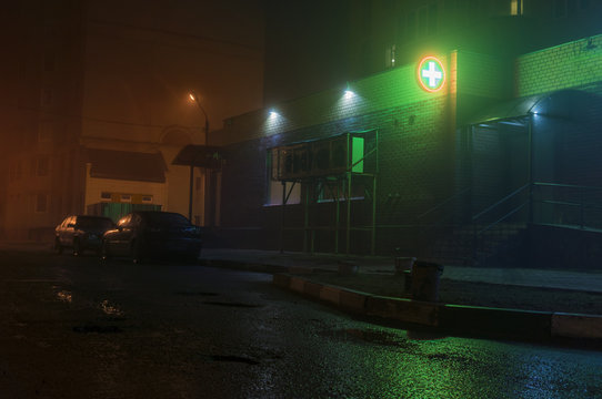 Fototapete - Street with fog and green pharmacie cross