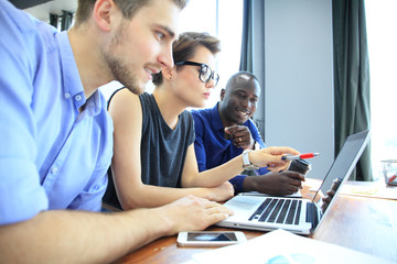 Wall Mural - Teamwork,brainstorming concept.Young creative managers team working with new startup project in modern office. Contemporary notebook on wood table.Horizontal, film effect