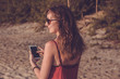 © allenkayaa - Young woman in red dress with smartphone on the beach