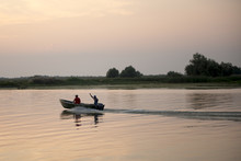 Scenic View Of Quiet Landscape With Silhouette Of A Fisherman’s Boat In Danube Delta Area, Romania, At Sunset Time