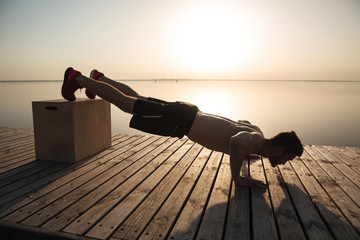 Wall Mural - Young healthy man doing push-ups with special equipment