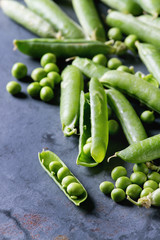 Young organic green pea pods and peas over blue gray texture metal background. Close up with space. Harvest, healthy eating.