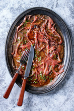 Asian Style Beef Carpaccio With Soy Sauce, Chive Onion, Black Sesame, Served On Vintage Metal Tray With Knife And Fork Over Gray Texture Background. Top View With Space