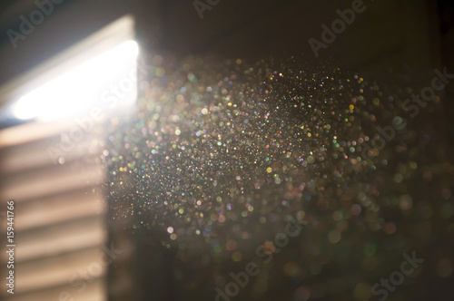Fotografía A ray of sun coming through the wooden shutters, illuminates dust on the inside of a dark room