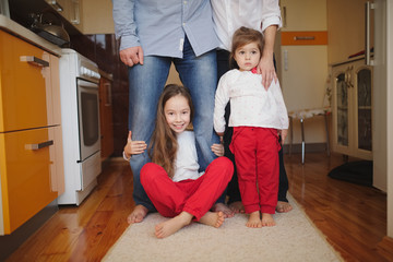 Wall Mural - little girls hugging mom and dad for legs