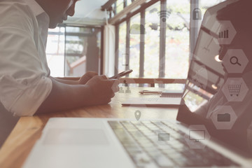 businessman using smart phone while sitting with laptop on table at office with communication and internet icon