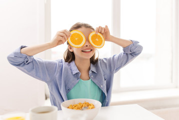 happy girl with orange having breakfast at home