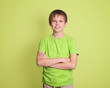 Confident preteen boy portrait with arms crossed isolated on green background.