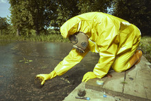Man In Chemical Protective Suit Collecting Samples Of Water Contamination