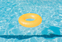 Bright Orange Float In Blue Swimming Pool, Ring Floating In A Refreshing Blue Swimming Pool With Wave Reflecting In The Summer Sun. Active Vacation Background, Lifesaver For Kid. Sunny Day At The Pool