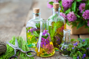Wall Mural - bottles of tincture or infusion of healing herbs, scissors, medicinal herbs on wooden board. herbal 