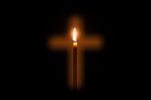 Candle Is Glowing Through Hole In Shape Of Christian Cross
