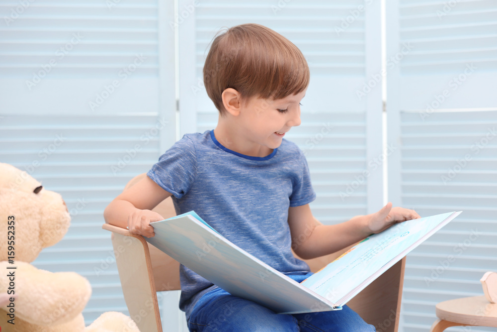 Cute little boy reading book at home