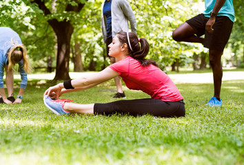 Group of young runners stretching and warming up in park.