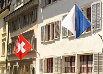 Canvas Print - Swiss Flag and Flag of Zurich on the facade building in Zurich, Switzerland