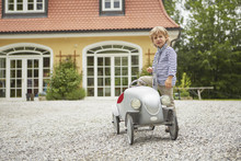 Boy Playing With Vintage Toy Car In Front Of House