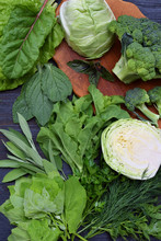 Composition On A Dark Background Of Green Leafy Vegetables Containing Folic Acid, Riboflavin, Vitamin B9, B2, K, C - Cabbage, Broccoli, Chard, Lettuce, Spinach, Parsley, Celery, Dill, Sage. Top View.