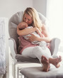 © Daniel Grill Images/Tetra Images - Mother sitting in armchair and kissing baby son (0-1 months)