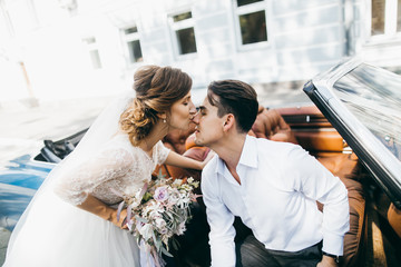 Just married couple in the blue retro car on their wedding