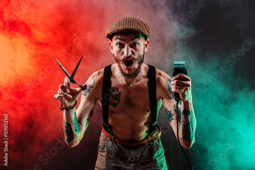 Cuadros en Lienzo Elegante tatuado barbero sin camisa gangsta hombre con maquinilla de afeitar mirando a la cámara
