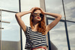 © SHOTPRIME STUDIO - Woman with glasses holds her head on the background of the building